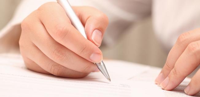 Hand completing an application form with a pen